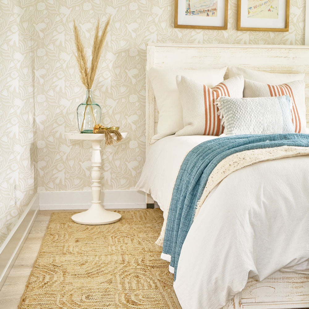 Image of a bedroom with a neutral color wallpaper paired with a jute rug