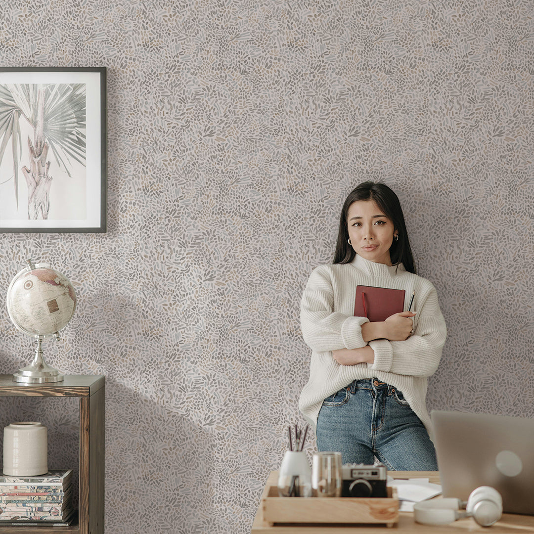 Neutral gray wallpaper on a wall with a college student in dorm standing in front of it. #color_stone-grey-daubs