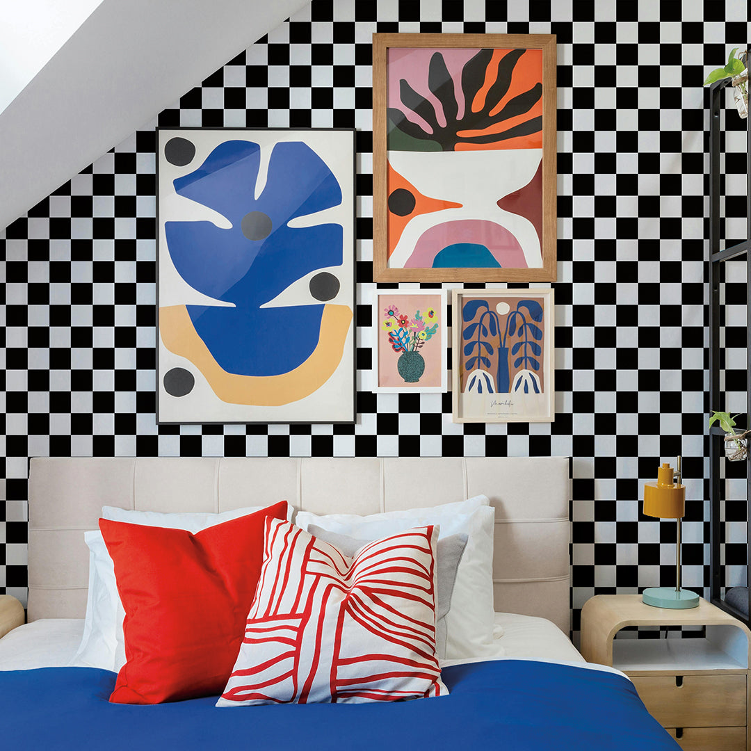 A dorm room that has a black and white checkered removable wallpaper on the wall behind a bed along with a gallery wall of artwork. #color_black-and-white-check