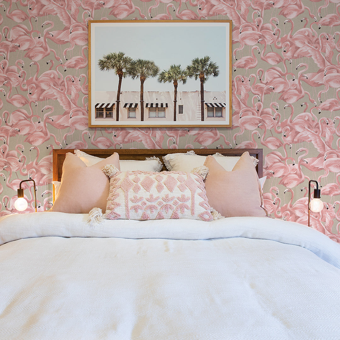 A college students dorm room with pink flamingo print removable wallpaper by Tempaper behind the bed. #color_ballerina-pink