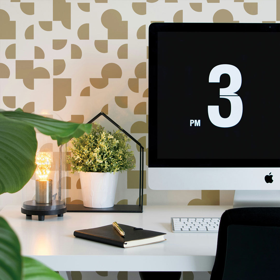 A desk with an apple computer in front of a wall featuring modern geometric peel and stick wallpaper. #color_soiree-gold
