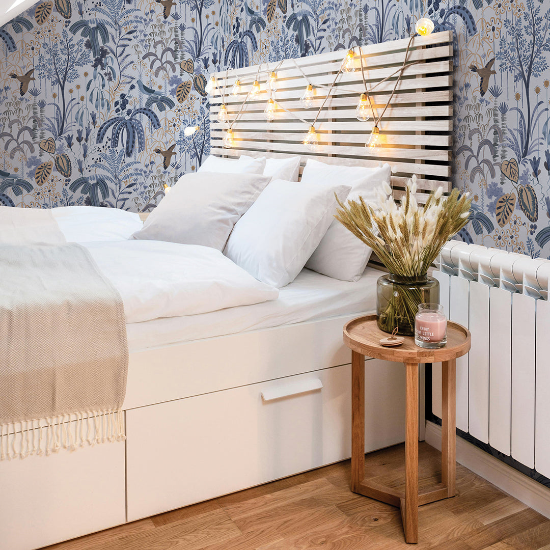 A dorm room with bed and wooden headboard and string lights featuring a wall of flora and fauna print peel and stick wallpaper #color_blue-blossom