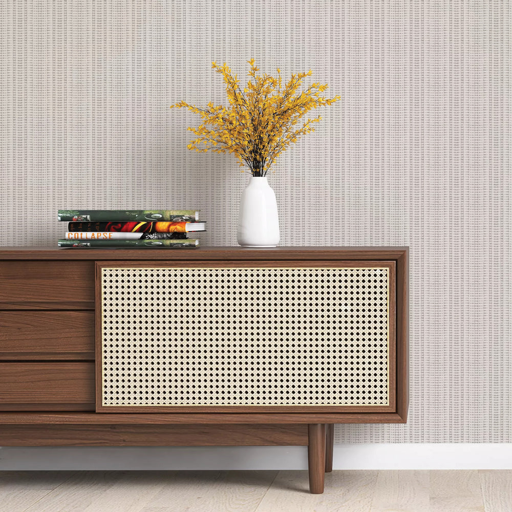 Batik Stripe Removable Wallpaper - A wood sideboard with books and a white vase on top in a room featuring Batik Stripe Peel And Stick Wallpaper in french grey | Tempaper#color_french-grey