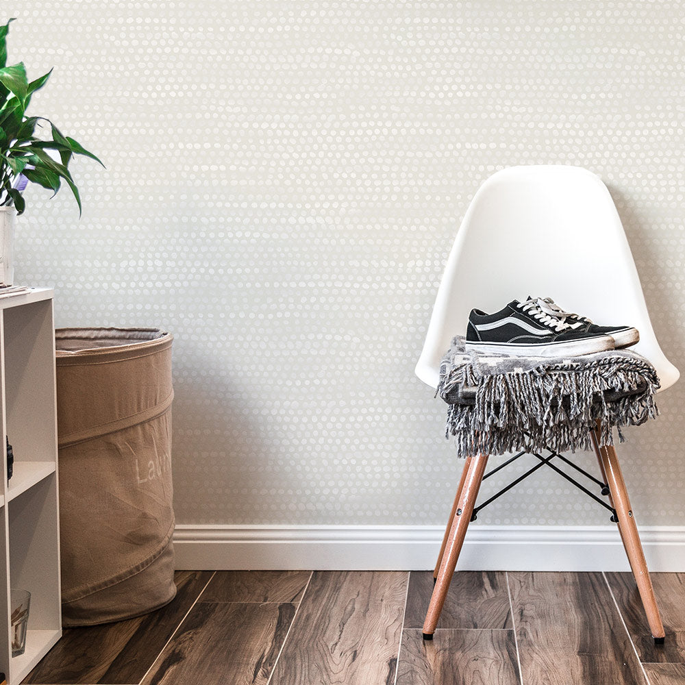 Moire Dots Removable Wallpaper - A white chair and white shelves in front of a wall featuring Tempaper's Moire Dots Peel And Stick Wallpaper in pearl grey dots | Tempaper#color_pearl-grey-dots