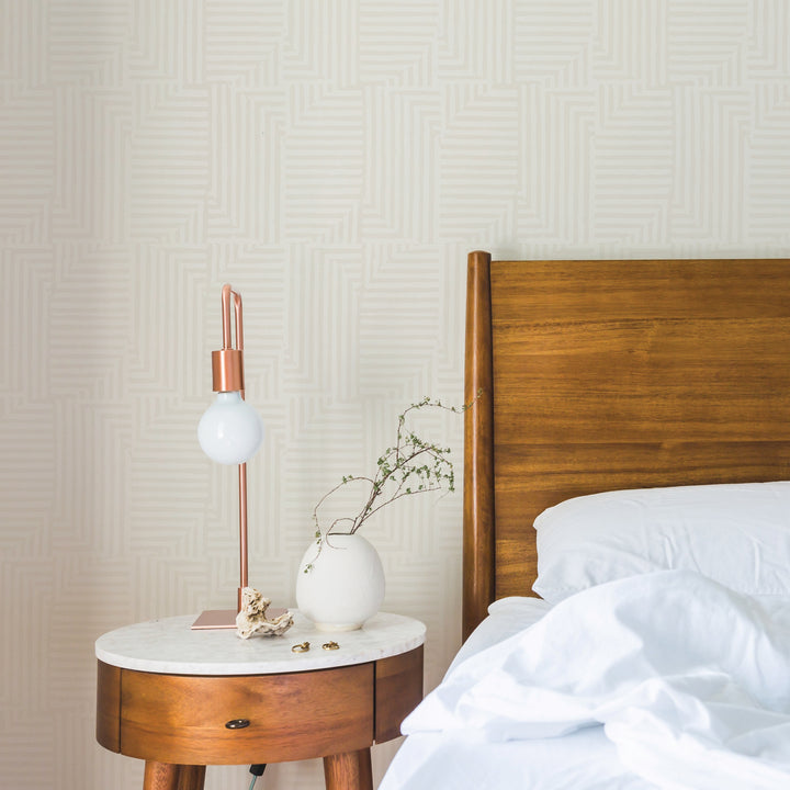 Tempaper's Geometric Patchwork Peel And Stick Wallpaper in a bedroom behind a bed and wood nightstand.