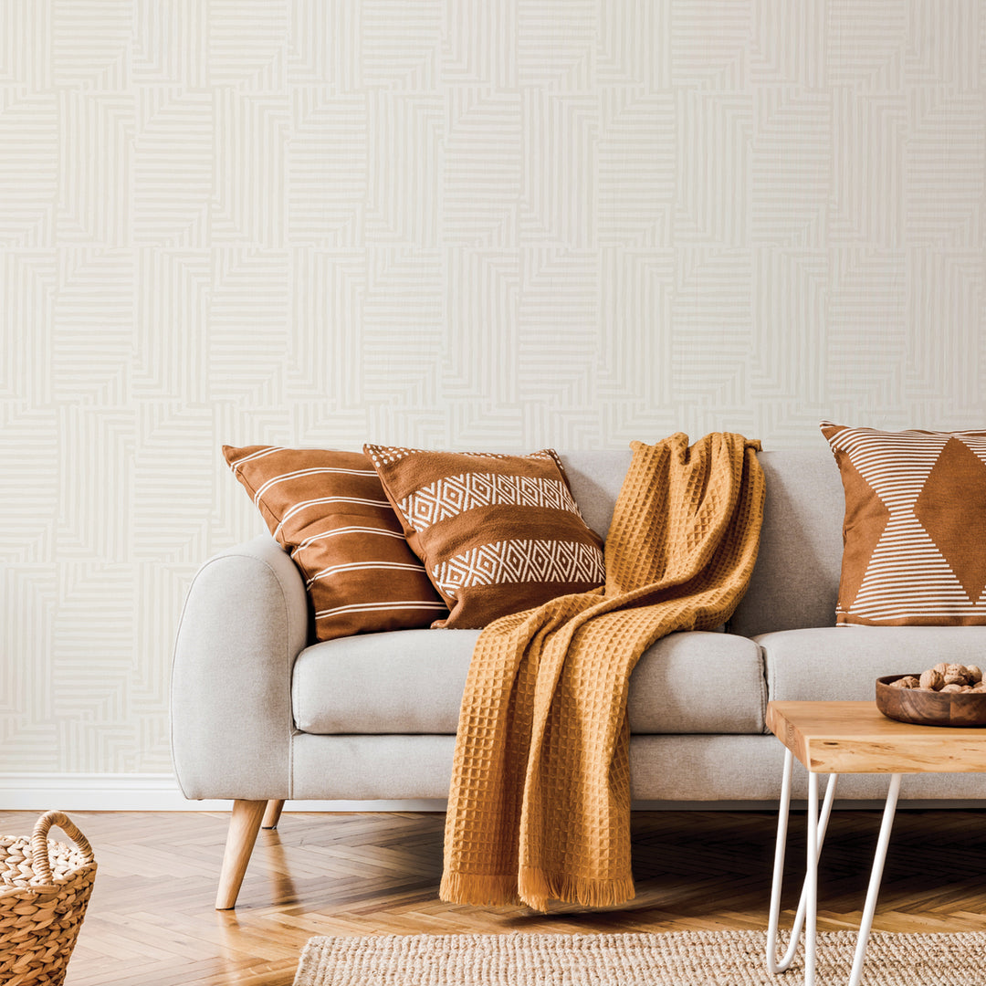 A grey couch with three brown pillows and Tempaper's Geometric Patchwork Temporary Wallpaper.