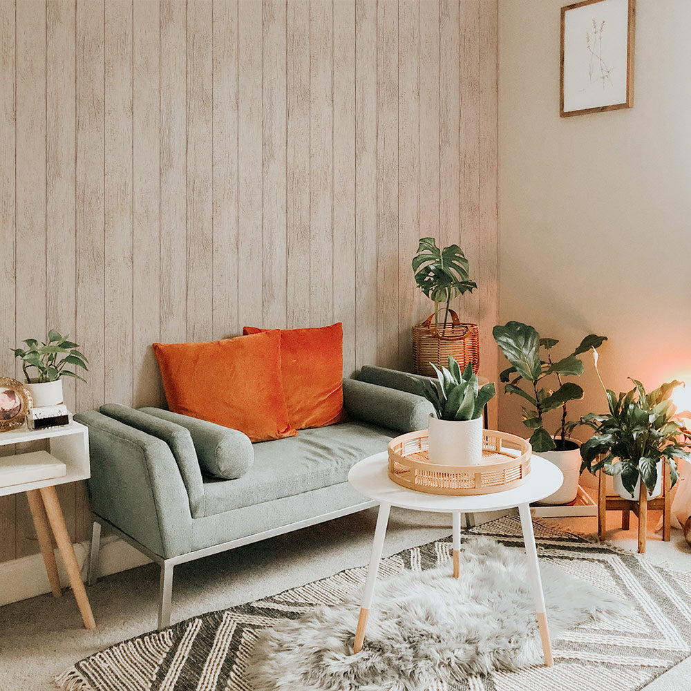 Tempaper's Farmhouse Planks Peel And Stick Wallpaper shown behind a couch, plants, and a table.