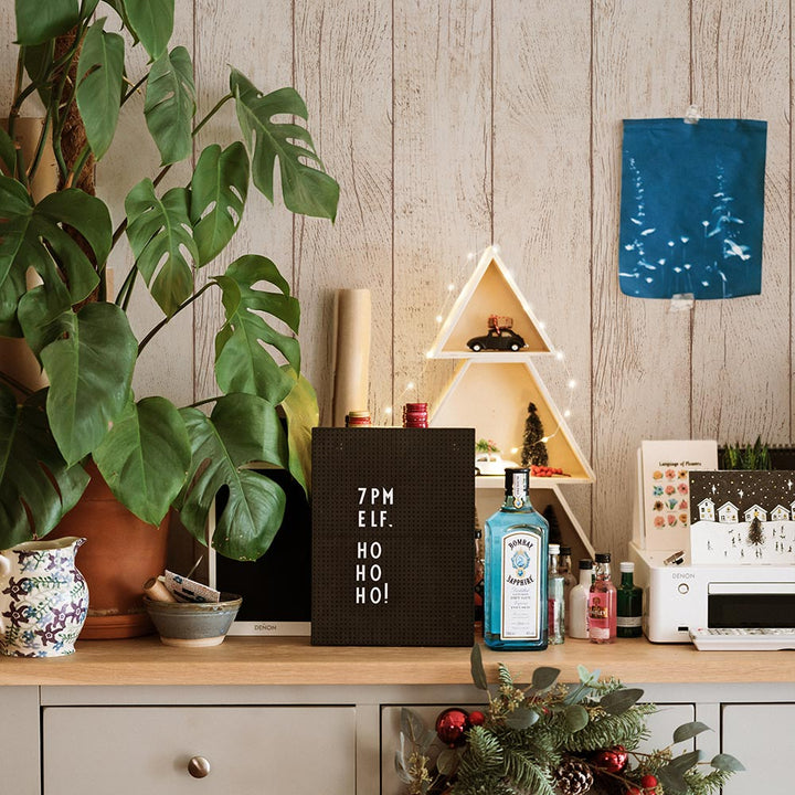 Tempaper's Farmhouse Planks Peel And Stick Wallpaper shown above a dresser behind plants.