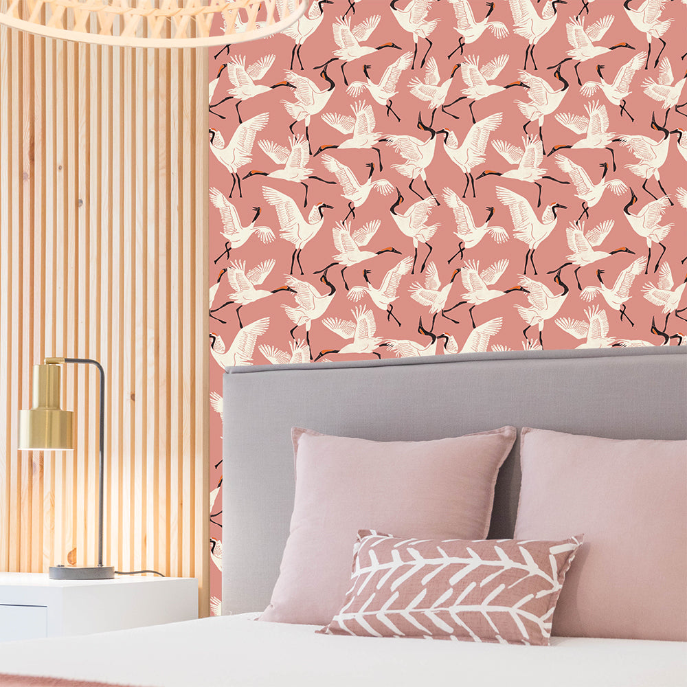 Tempaper's Family of Cranes Peel And Stick Wallpaper By Novogratz shown in a bedroom above a bed. #color_dusty-rose