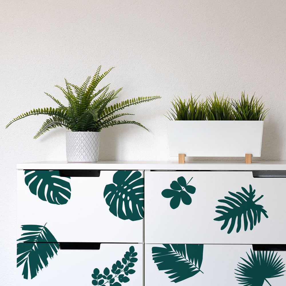 Tempaper's Graphic Palm Leaf Wall Decals on a white dresser with two plants on top.