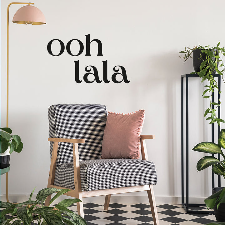 A room with checkered flooring plants, and a black and white chair decorated using Tempaper's black Ooh La La wall decals.