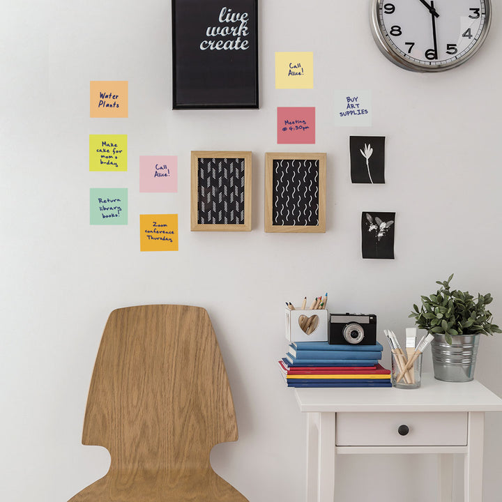 Tempaper's Dry Erase Sticky Notes Wall Decals shown above a chair next to picture frames and a clock.