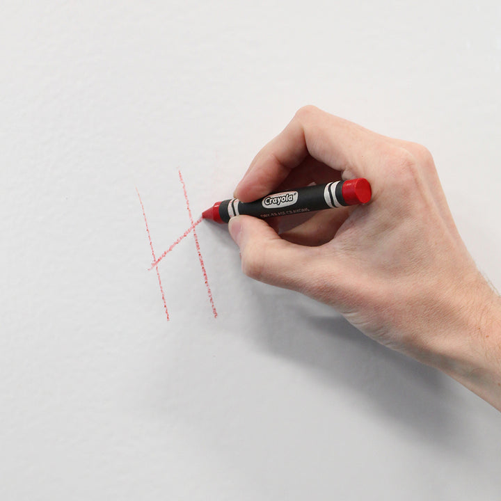 A hand using Crayola's Dry Erase Crayons on a wall.